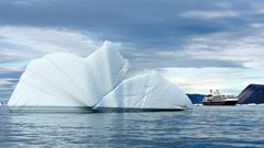 Eisberg in einer Bucht in Grönland mit Ponant Expeditionsschiff