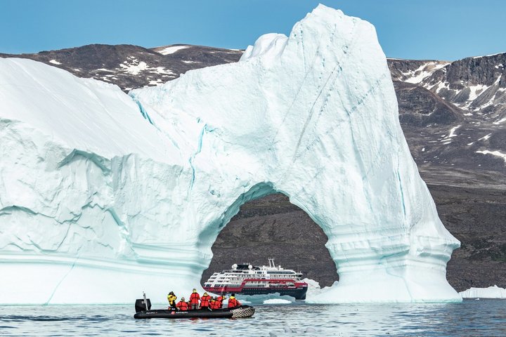 Zodiac und Hurtigrutenschiff um schwimmenden Eisberg