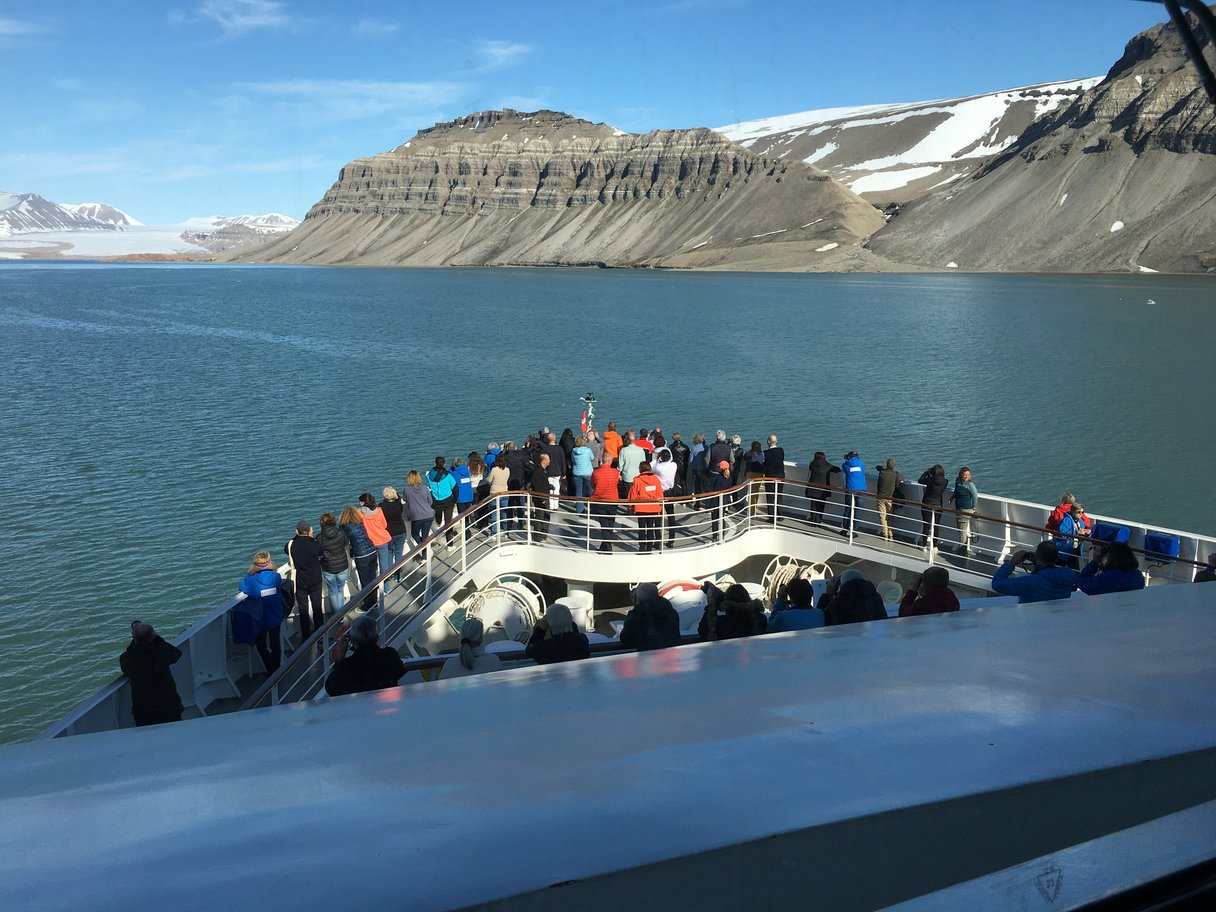 Fjord in Spitzbergen mit Schiffbug und Passagieren im Vordergrund