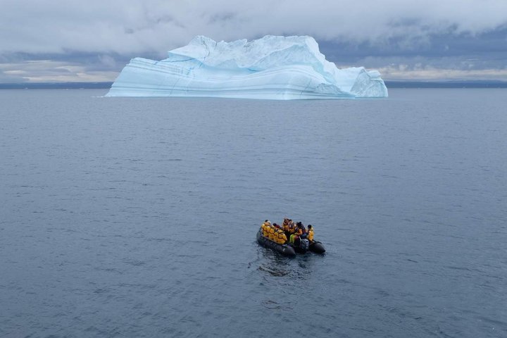 Zodiac in einer Bucht mit Eisberg im Hintergrund