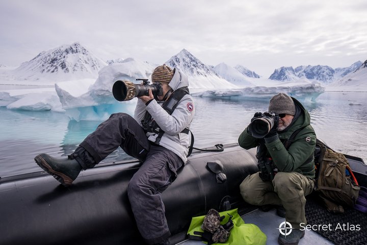 Zwei Fotografen auf einem Zodiac mit Bergen im Hintergrund
