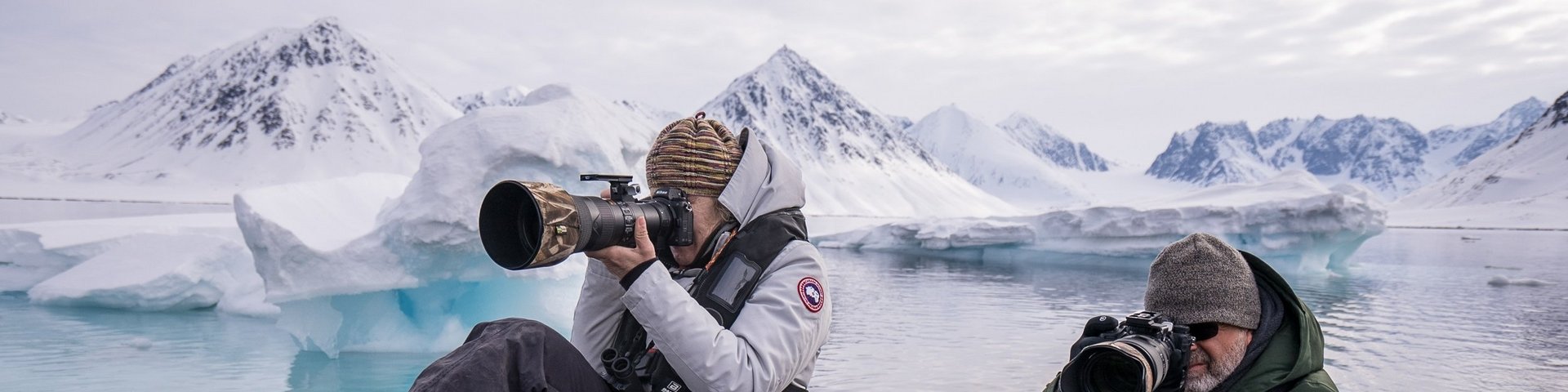 Zwei Fotografen auf einem Zodiac mit Bergen im Hintergrund