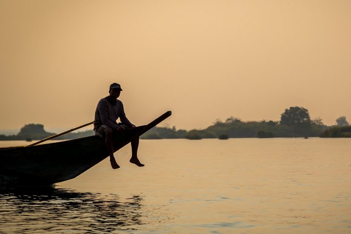 Fischer auf seinem Boot in Laos bei Sonnenuntergang