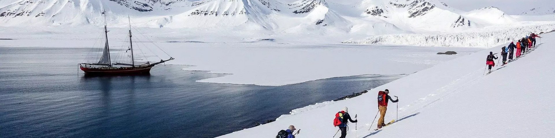 Skitourengänger in Norwegen mit Segelschiff im Hintergrund