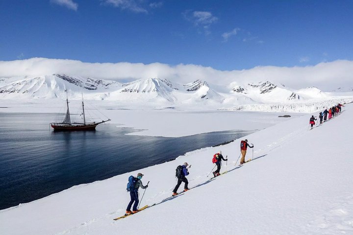 Skitourengänger in Norwegen mit Segelschiff im Hintergrund