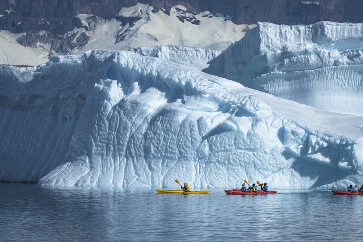 Kajaks paddeln entlang einem Eisberg in der Antarktis