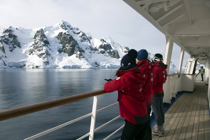 Passagiere an der Reling mit Bergen der Antarktis